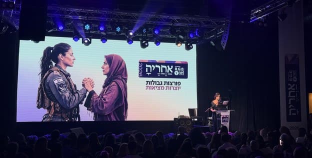 A speaker on stage in front of the After Her screen
